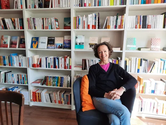 une femme assise dans un fauteuil devant des rayonnages de livres